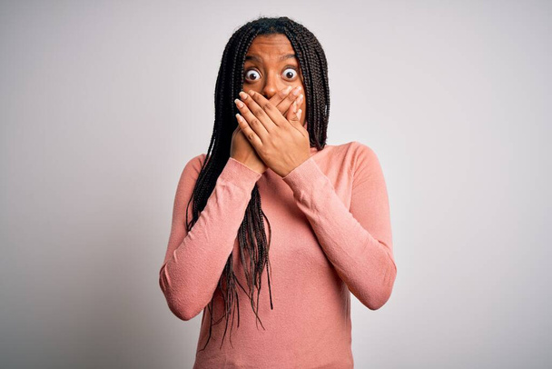Une jeune Américaine africaine se tenant debout et fraîche sur fond blanc et isolé a été choquée de se couvrir la bouche avec les mains par erreur. Concept secret. - Photo, image