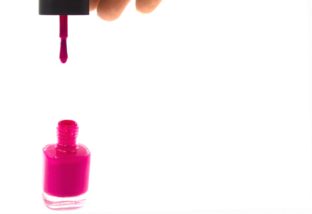 Esmalte de uñas rosa goteando del cepillo en botella sobre fondo blanco. Espacio para el texto. Burlarse. Vista lateral
 - Foto, Imagen