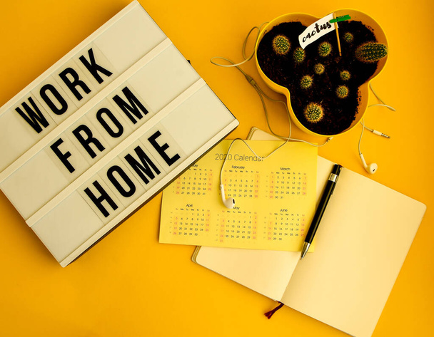 lightbox s textem WORK FROM HOME with notebook pen and calendar 2020 to DO list, copy space on yellow background, karanténa and isolation HOME OFFICE, coronavirus, europe - Fotografie, Obrázek
