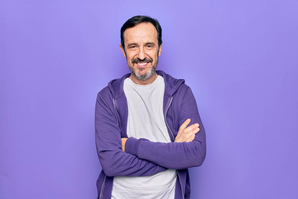 Middle age handsome sporty man wearing casual purple sweatshirt over isolated background happy face smiling with crossed arms looking at the camera. Positive person. - Photo, Image