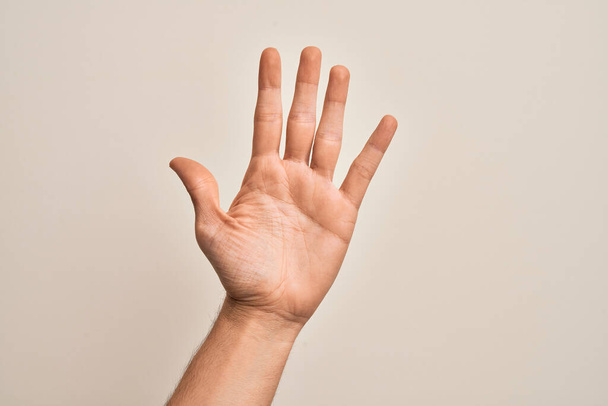 Mano de joven caucásico mostrando dedos sobre fondo blanco aislado contando número 5 mostrando cinco dedos - Foto, imagen