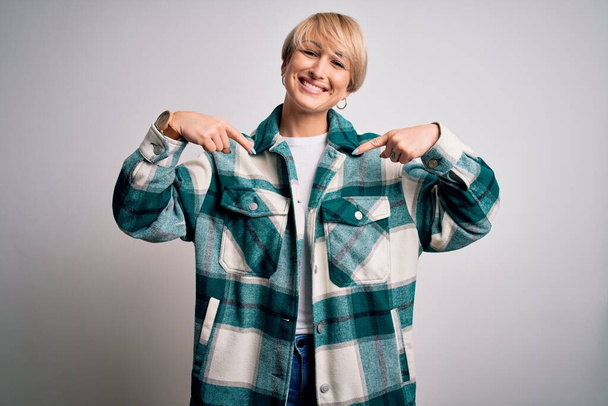 Young blonde woman with short hair wearing casual retro green shirt over isolated background looking confident with smile on face, pointing oneself with fingers proud and happy. - Valokuva, kuva