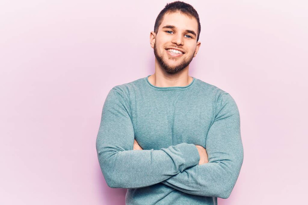 Young handsome man wearing casual sweater happy face smiling with crossed arms looking at the camera. positive person.  - Photo, Image