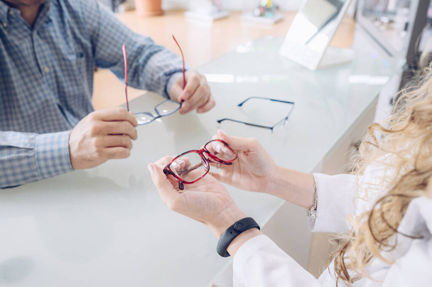 Blond optometrist vrouw tonen verschillende modellen van bril naar een klant. - Foto, afbeelding