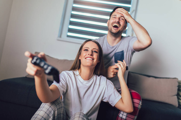 Jeune couple ludique jouant à des jeux vidéo dans leur salon
. - Photo, image