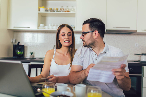 Manžel a manželka spolu dělají papírování, platí daně online na notebooku. - Fotografie, Obrázek