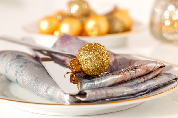 silver cutlery decorated with a golden Christmas bauble, with co - Фото, зображення