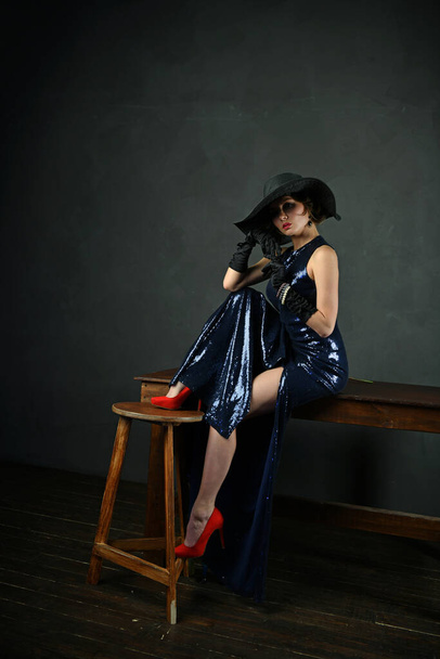 belle femme dans une robe de soirée bleue en gants noirs et un chapeau noir et avec un pistolet
 - Photo, image