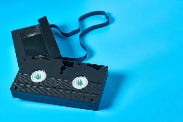 Two black old plastic vhs video cassettes lies on blue desk. Concept of 90s. Copy space - Zdjęcie, obraz