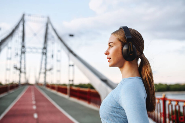 Tyttö urheiluvaatteet kanssa kuulokkeet sillalla
 - Valokuva, kuva
