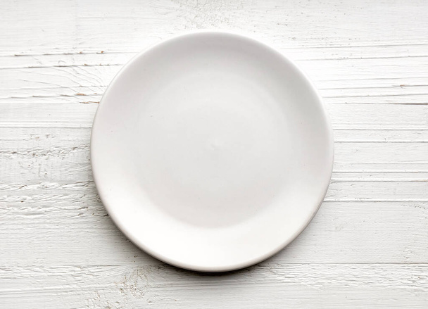 leerer weißer Teller auf weißem Holzhintergrund, Draufsicht - Foto, Bild