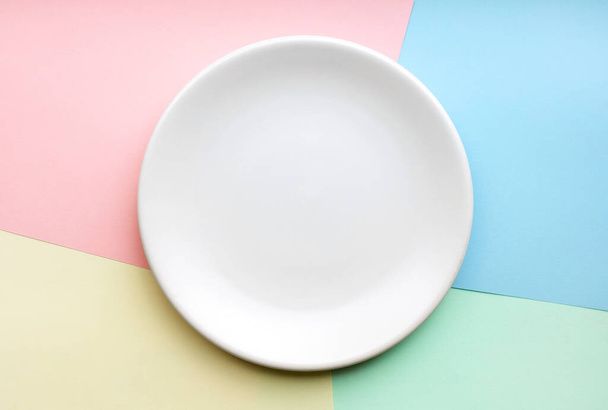 empty white plate on colored paper background, top view - Foto, immagini