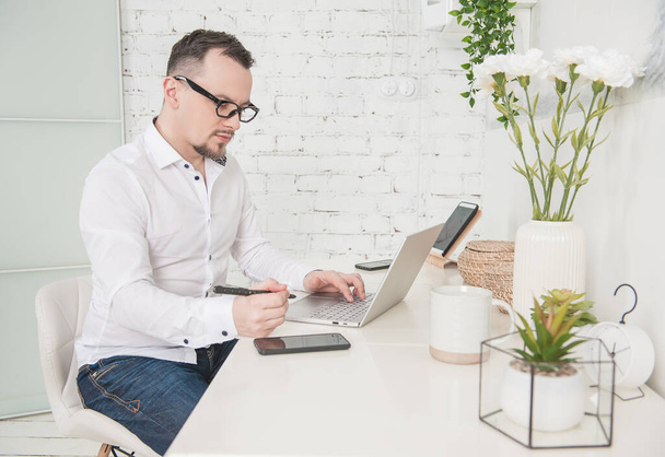 Liikemies käyttää kannettavaa tietokonetta ja älypuhelinta kotona. Freelance tai etäopiskelun käsite
 - Valokuva, kuva