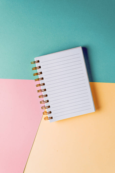 Nyílt notebook üres lap és arany spirál színes pasztell háttér. Az oktatás fogalma, az ötletek, tervek leírása. Helyet az sms-nek. Minimalizmus, lapos fektetés. - Fotó, kép