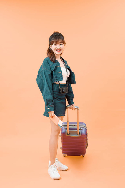 Girl with a suitcase going traveling on color background - Fotó, kép
