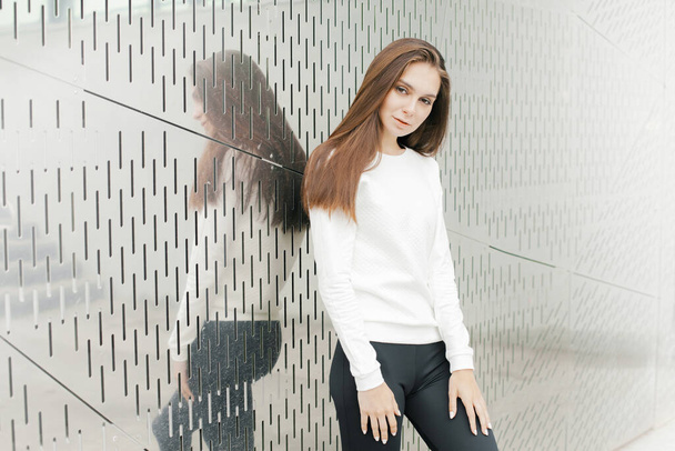 Young woman in white sweater and black leggings. Lifestyle, beauty, walking outdoors - 写真・画像