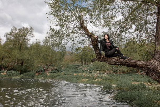 Girl sitting on a tree above the water in the river - Fotografie, Obrázek
