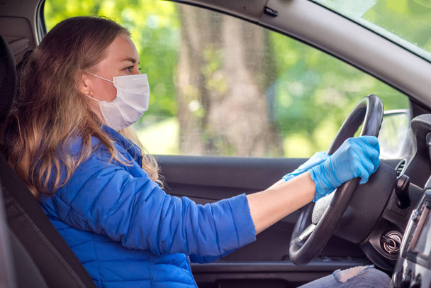 A woman driving a car in a protective medical mask and gloves. Lifestyle and safe drive during a pandemic coronavirus in quarantine. Protect the driver and passengers. New normal and modern reality - Fotó, kép