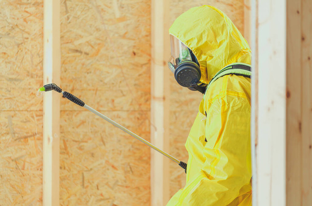 Caucasian Worker in Safe Breathing Mask and Hazmat Suit Disinfection Newly Developed Building Interior. - 写真・画像