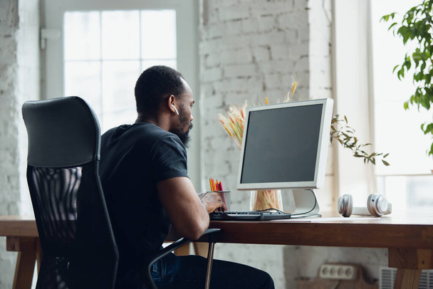 Mladý muž, obchodník pracující v kanceláři, dívající se na prázdnou černou obrazovku počítače, monitor. Copyspace. - Fotografie, Obrázek