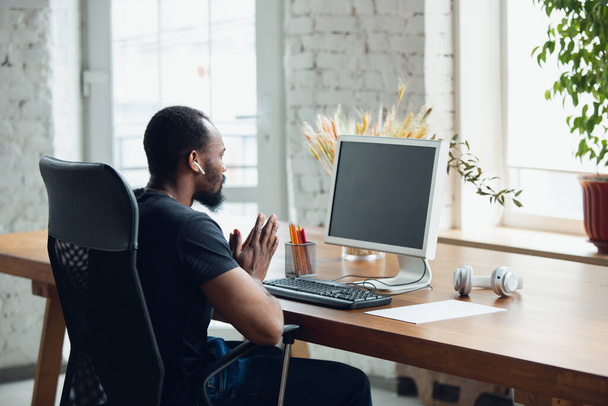 Young man, businessman working in office, looking on blank black computer screen, monitor. Copyspace. - Fotoğraf, Görsel