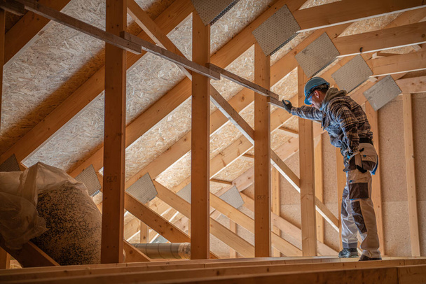 Empreiteiro de Construção Caucasiano Trabalhador na casa dos 30 anos Verificando a estrutura de madeira do sótão e telhado. Tema industrial
 - Foto, Imagem
