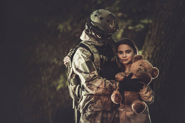 Bělošský voják ve třiceti v maskovacím obleku Návrat z vojenské mise a setkání se svou dcerou. Rodina se sjednotila. Dívka s medvídkem v rukou, kterou dostala jako dárek od svého otce.  - Fotografie, Obrázek