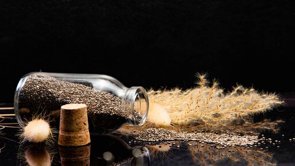 close-up view of healthy chia seeds and glass jar on black background - Fotografie, Obrázek