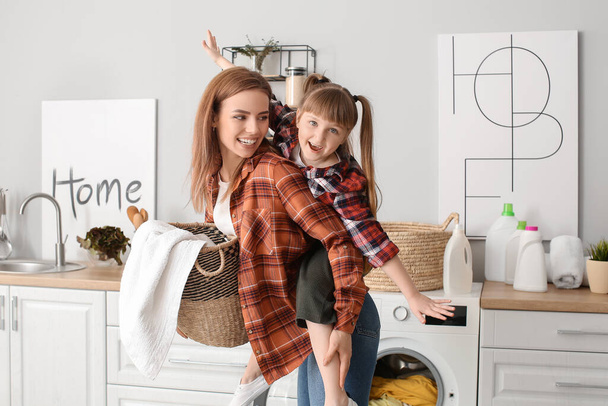 Nainen ja hänen söpö pieni tyttärensä hauskaa pesemällä pyykkiä kotona
 - Valokuva, kuva