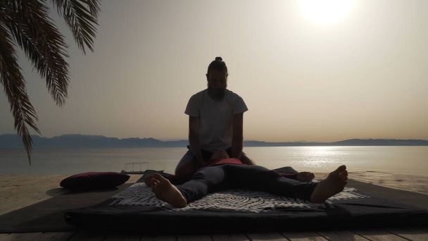 Силует масажиста робить тайський масаж йоги для жінки на світанку надворі
. - Фото, зображення