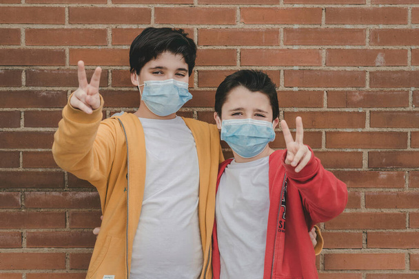 δύο παιδιά με ιατρική μάσκα κάνει πινακίδα νίκη εξωτερική - Φωτογραφία, εικόνα