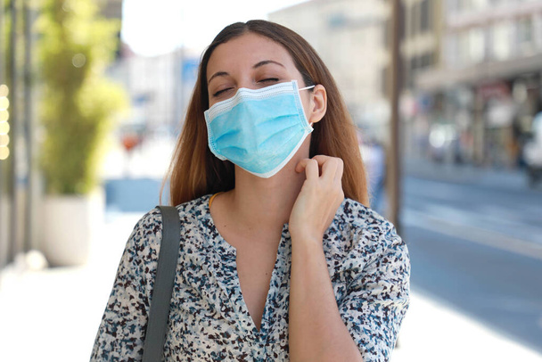 Fiatal nő sebészeti maszk viszketés allergia tünetek karcolás nyak a város utcájában - Fotó, kép