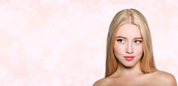 Portrait of beautiful blonde young woman face.  Spa model girl with fresh clean skin isolated on a blur pink background. Skin and hair care concept - Photo, image