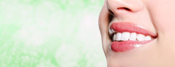 Beautiful woman smile with great white teeth on a blur green background. Dental and medical health care concept - Foto, Imagen