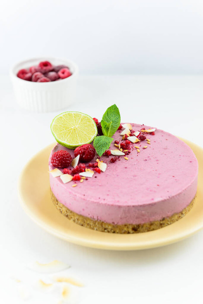 Homemade raw cashew cake with raspberries, mint and lime on a light table. Vegan dessert, sugar free, gluten free, lactose free. - Photo, Image