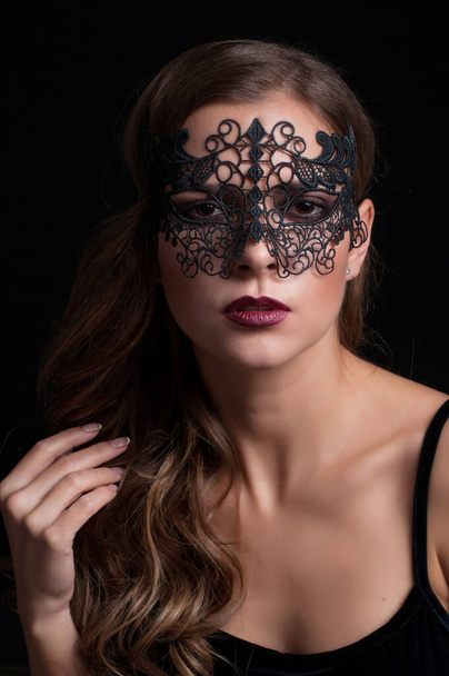 young pretty brunette woman in venetian lacy mask. close up portrait lacy mask. red lips make up. erotic passion woman image on black background - Fotoğraf, Görsel