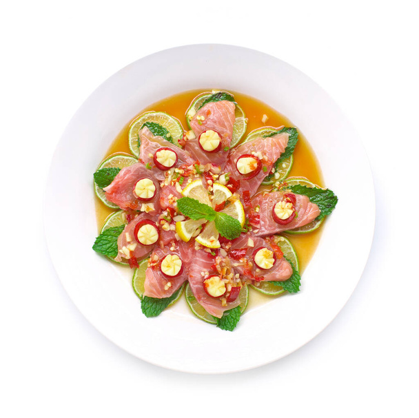 Salmon Spicy in Fish sauce and seafood sauce decorate with chili and garlic carved, lime, leaf mint Thai fusion appetizer goodtasty for healthy diet top view - Photo, Image