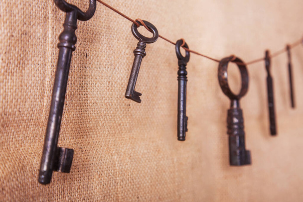 Several old rusty keys on a burlap background. Retro and vintage, steampunk. - Photo, Image