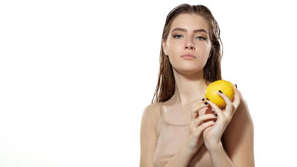 Vitamins. Beautiful young woman with lemon over white background. Cosmetics and makeup, natural and eco treatment, skin care. Flyer with copyspace. - Фото, изображение
