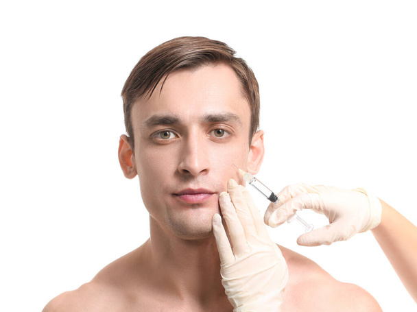 Handsome man receiving filler injection on white background - Фото, зображення