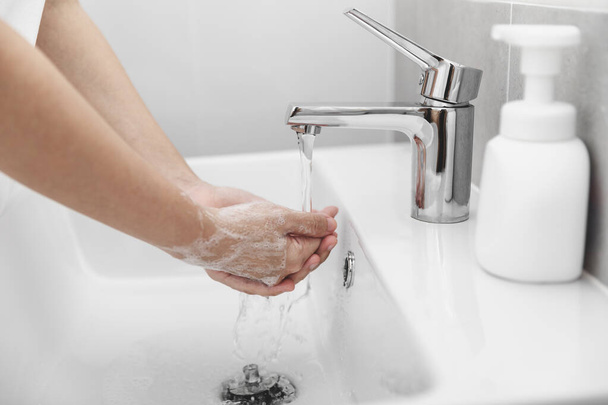 Kobieta używa mydła i mycia rąk pod kranem wody w celu zapobiegania wirusom korony, higieny, aby zatrzymać rozprzestrzenianie się koronawirusu. - Zdjęcie, obraz