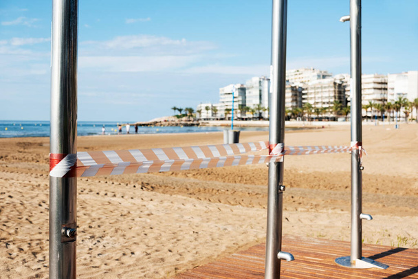 veřejná sprcha na pláži ve Středozemním moři uzavřená bezpečnostní páskou z důvodu kovid-19 omezení na používání veřejného prostoru - Fotografie, Obrázek