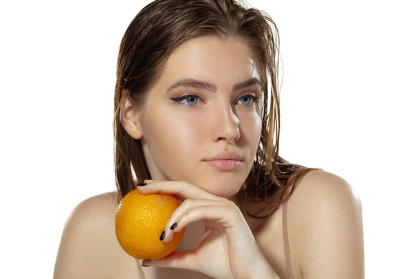 Skincare. Beautiful young woman with orange over white background. Cosmetics and makeup, natural and eco treatment. - Foto, Imagem