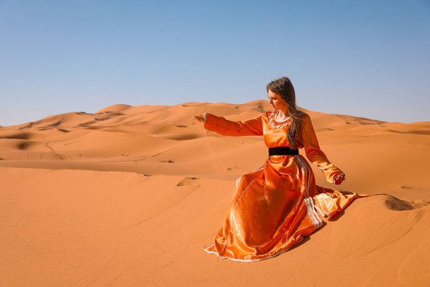 mooi jong meisje in Marokkaanse jurk in Sahara woestijn. - Foto, afbeelding