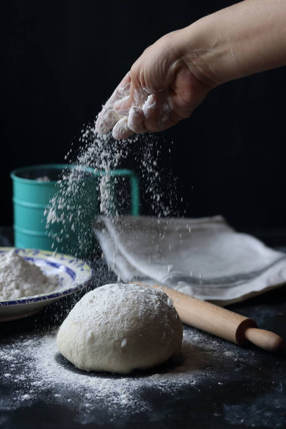 Dough ,making dough with flour on a black background, bread and pizza dough - Photo, image