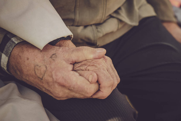 Ręka starszej kobiety trzymającej za rękę starszego mężczyzny. - Zdjęcie, obraz