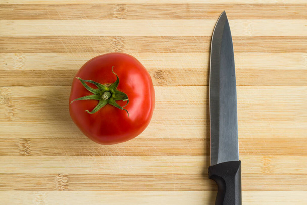 Krájené rajče s nožem na sekací desce, pohled shora. - Fotografie, Obrázek