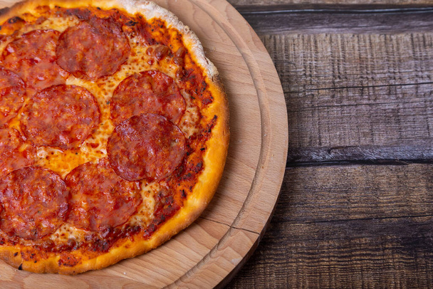 Pizza with chorizo sausage on a wooden board. Whole pizza. Close-up, place for text. - Foto, Bild