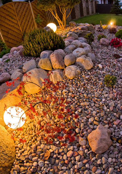 Hausgarten in der Nacht, beleuchtet von kugelförmigen Lichtern. Dekorative Garten- und Landschaftsgestaltung abstrakt. Saftiges Mai-Laub. - Foto, Bild
