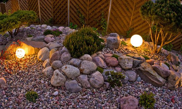 Hausgarten in der Nacht, beleuchtet von kugelförmigen Lichtern. Dekorative Garten- und Landschaftsgestaltung abstrakt. Saftiges Mai-Laub. - Foto, Bild